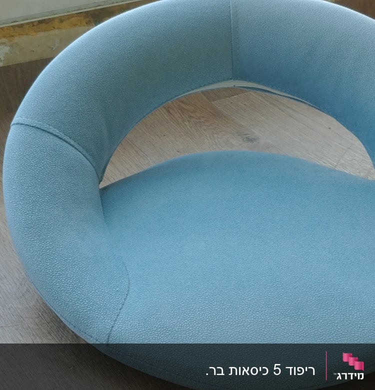 כרית עגולה מרופדת בצבע תכלת על שולחן עץ